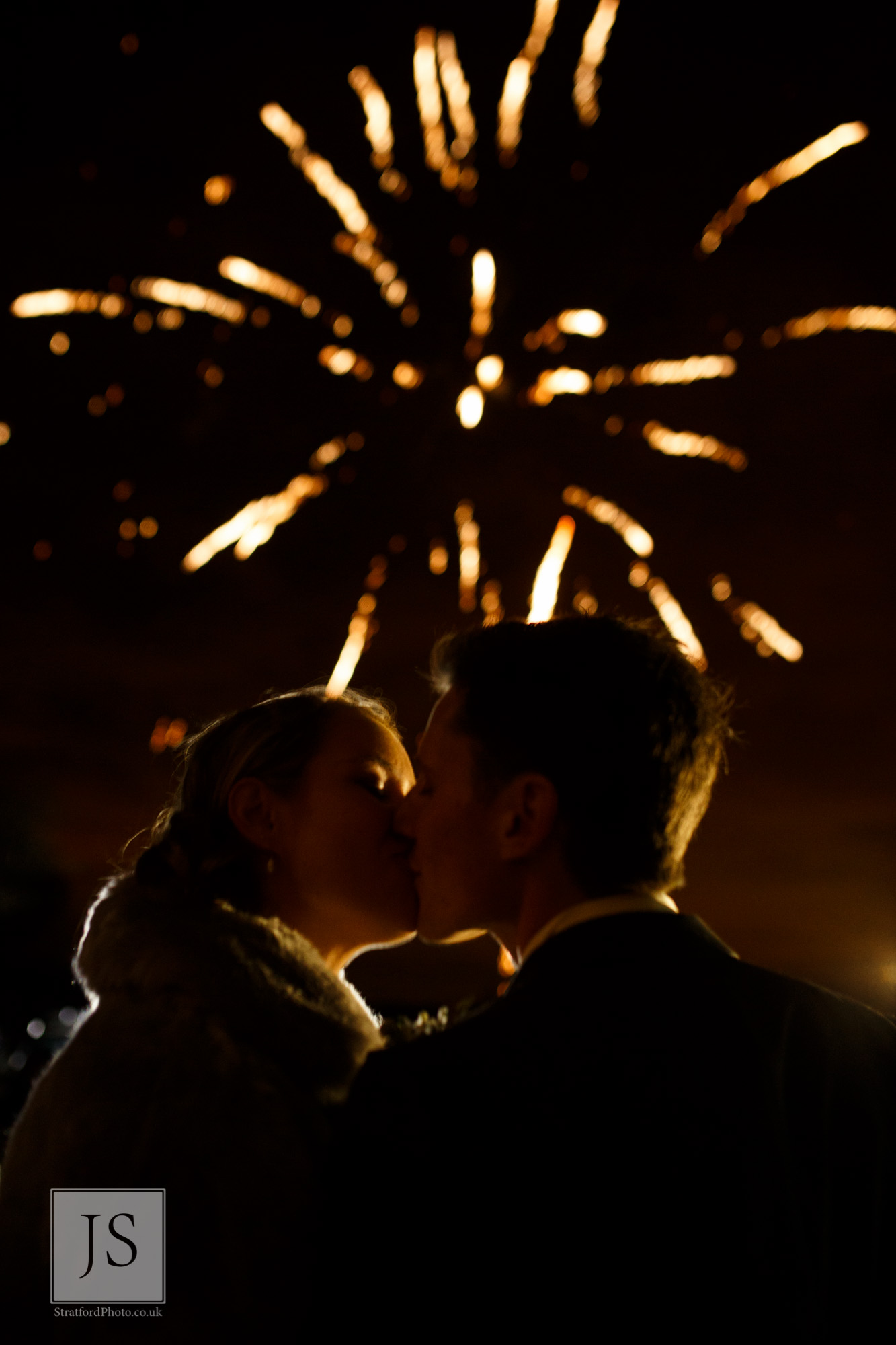 A bride and groom share a kiss before some fireworks.jpg