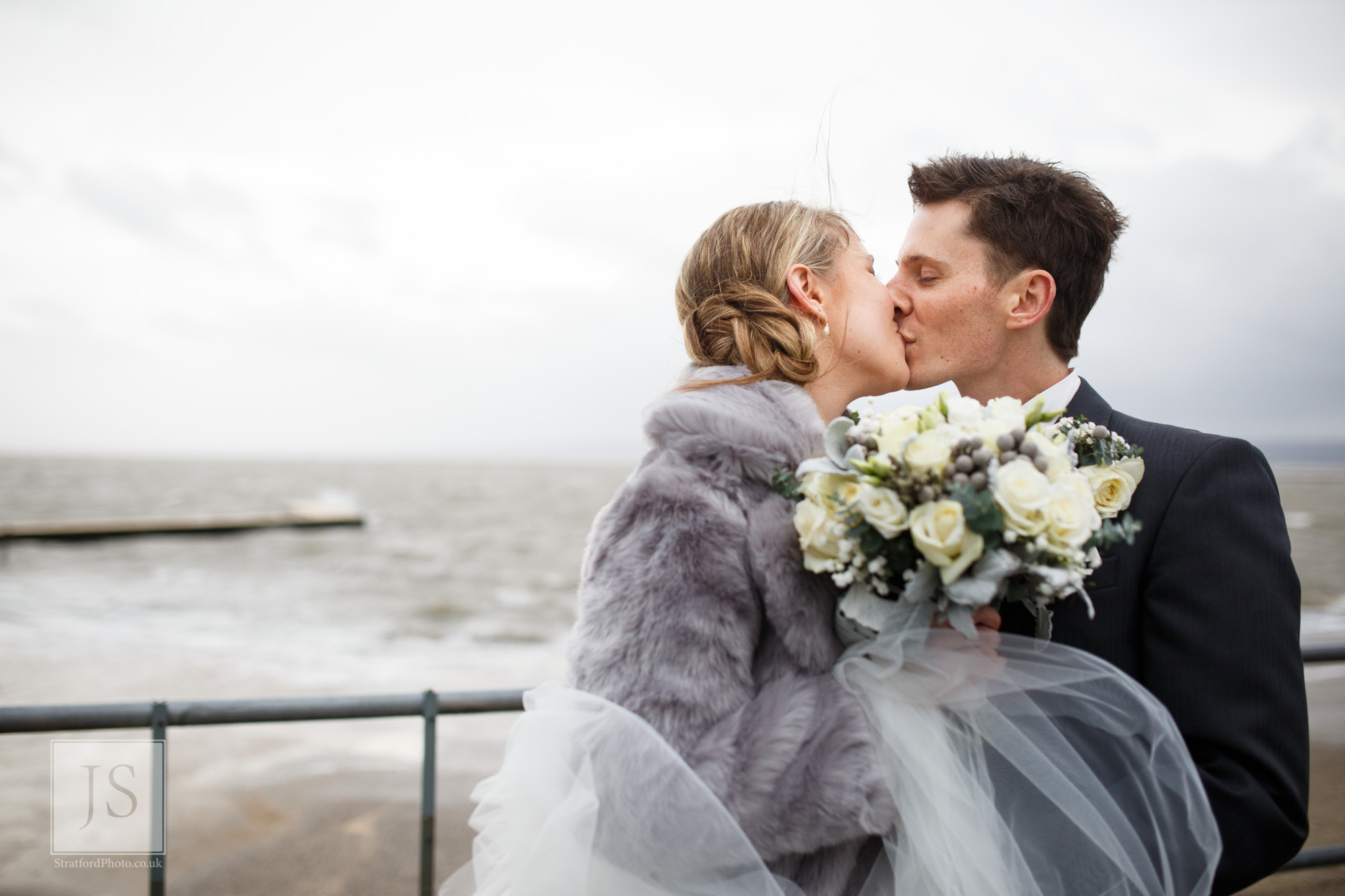 A bride and groom kiss by Marine Lake in Hoylake during Storm Desmon.jpg