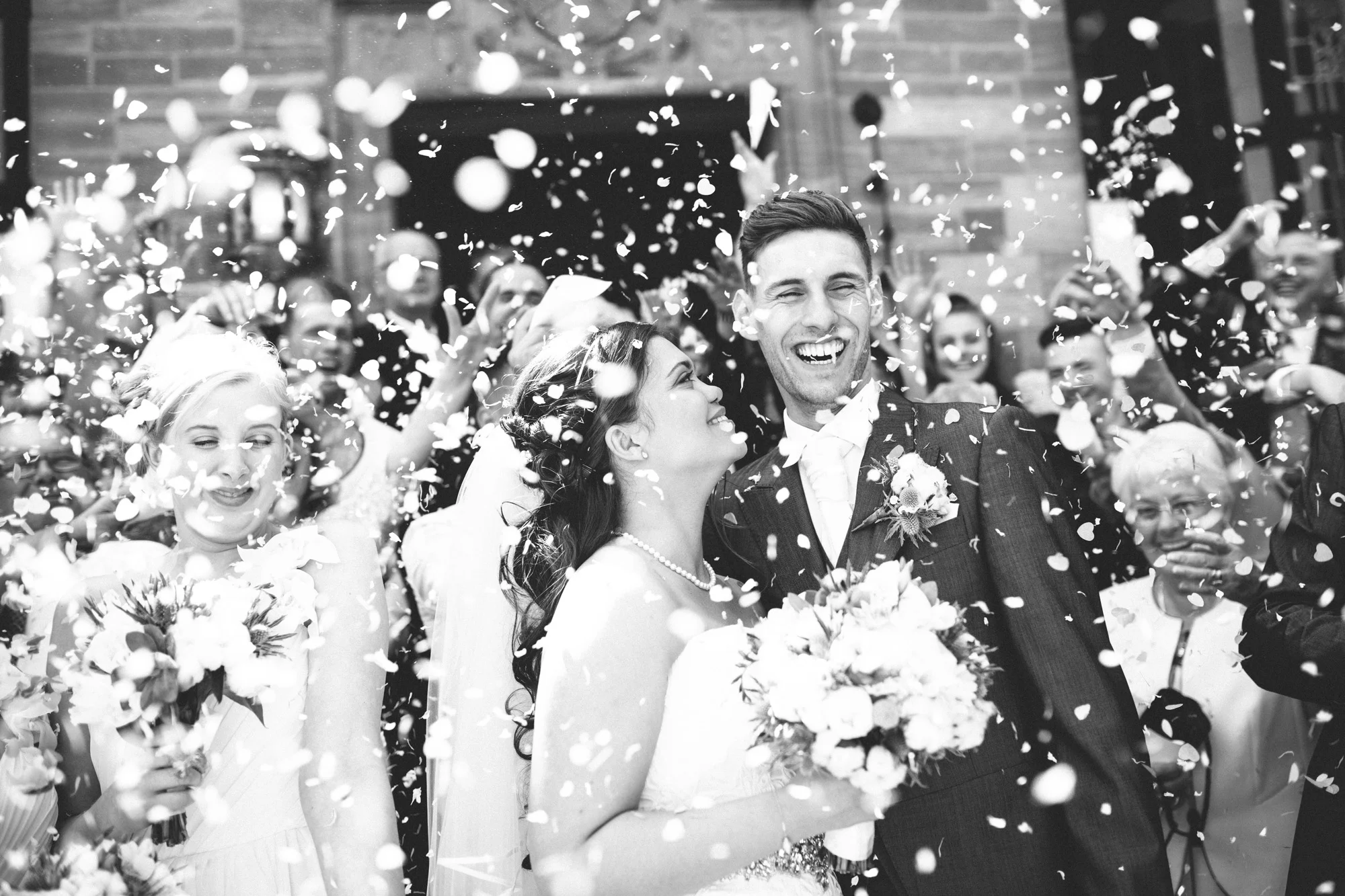 A bride and groom laugh under confetti on their wedding day