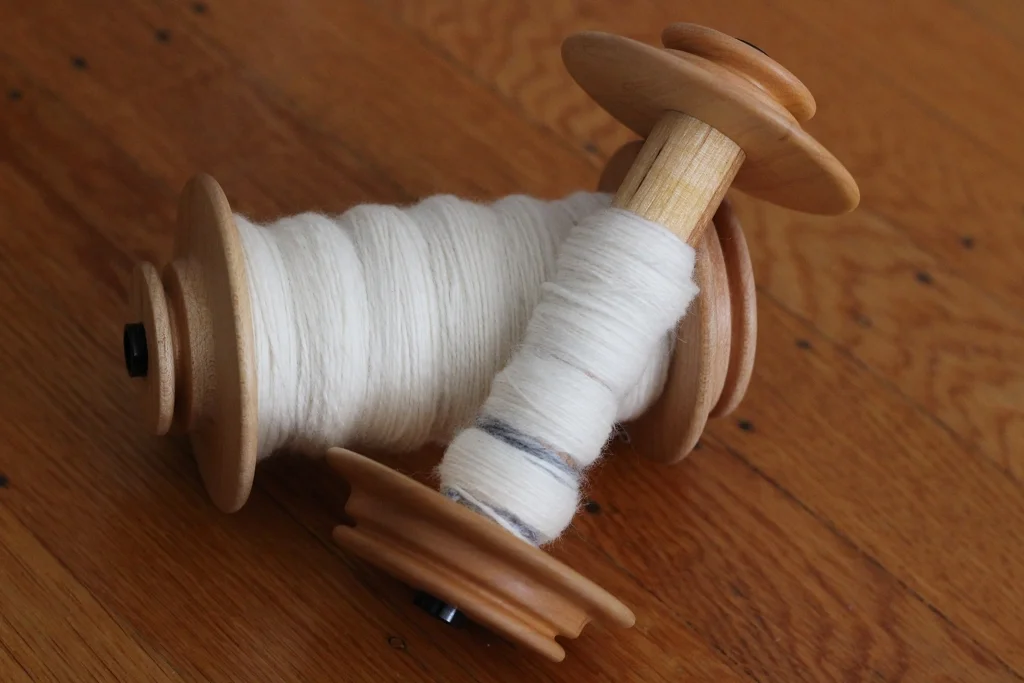 One mama skein and one baby skein of plied cashmere ready to come off the bobbins. Cashmere is as soft as everyone says it is, and here's how I turned 2 oz of it into yarn. | Notes About Spinning Cashmere - withwool.com