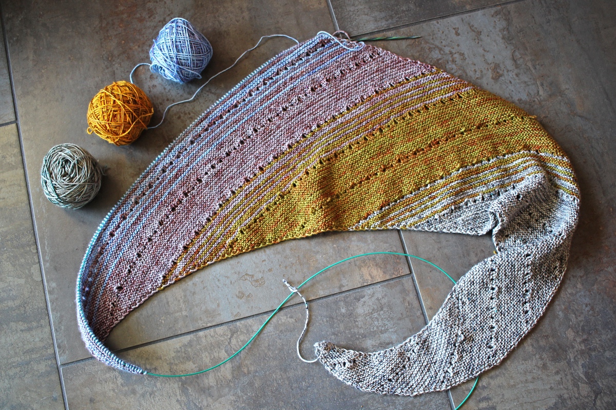 An overall photo showing the #FreeYourFade shawl with 4 colors knit and and 2 yarn balls waiting to be knit. Marginalia and Spreadsheets || withwool.com