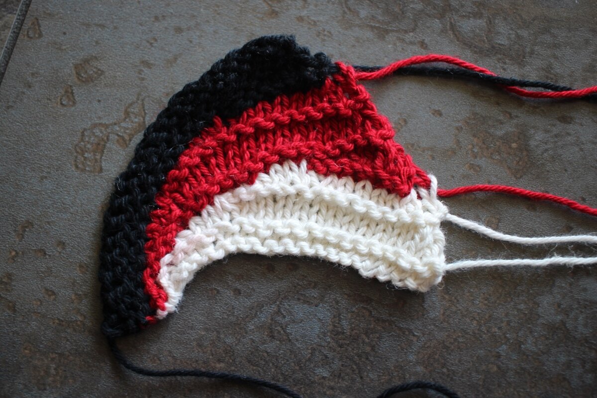 Red, white, and black swatch dry with ends hanging out. Sideways Swatching || withwool.com #knitswatch #darkmatterknits