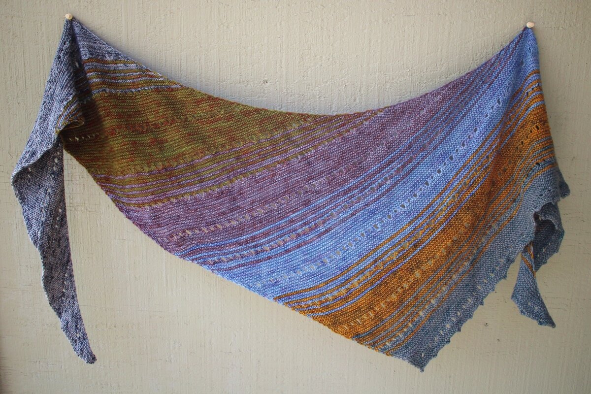 A finished Free Your Fade shawl hanging from a wall. #knitting #AndreaMowry Shawl Parade | withwool.com
