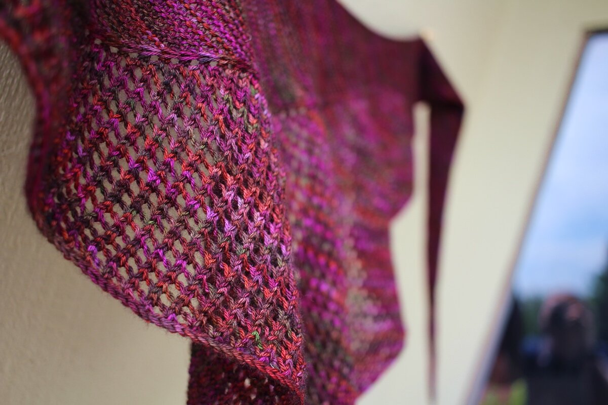 A close up of the mesh and variegated colors of the Curve of the Boat shawl. #knitting #hedgehogfibers Shawl Parade | withwool.com