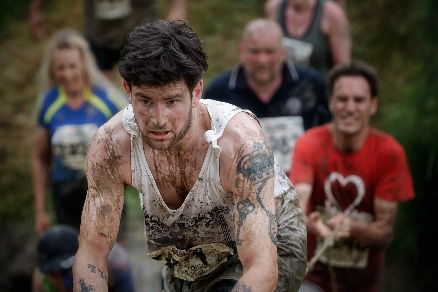 Mud runner receiving help over an obstacle