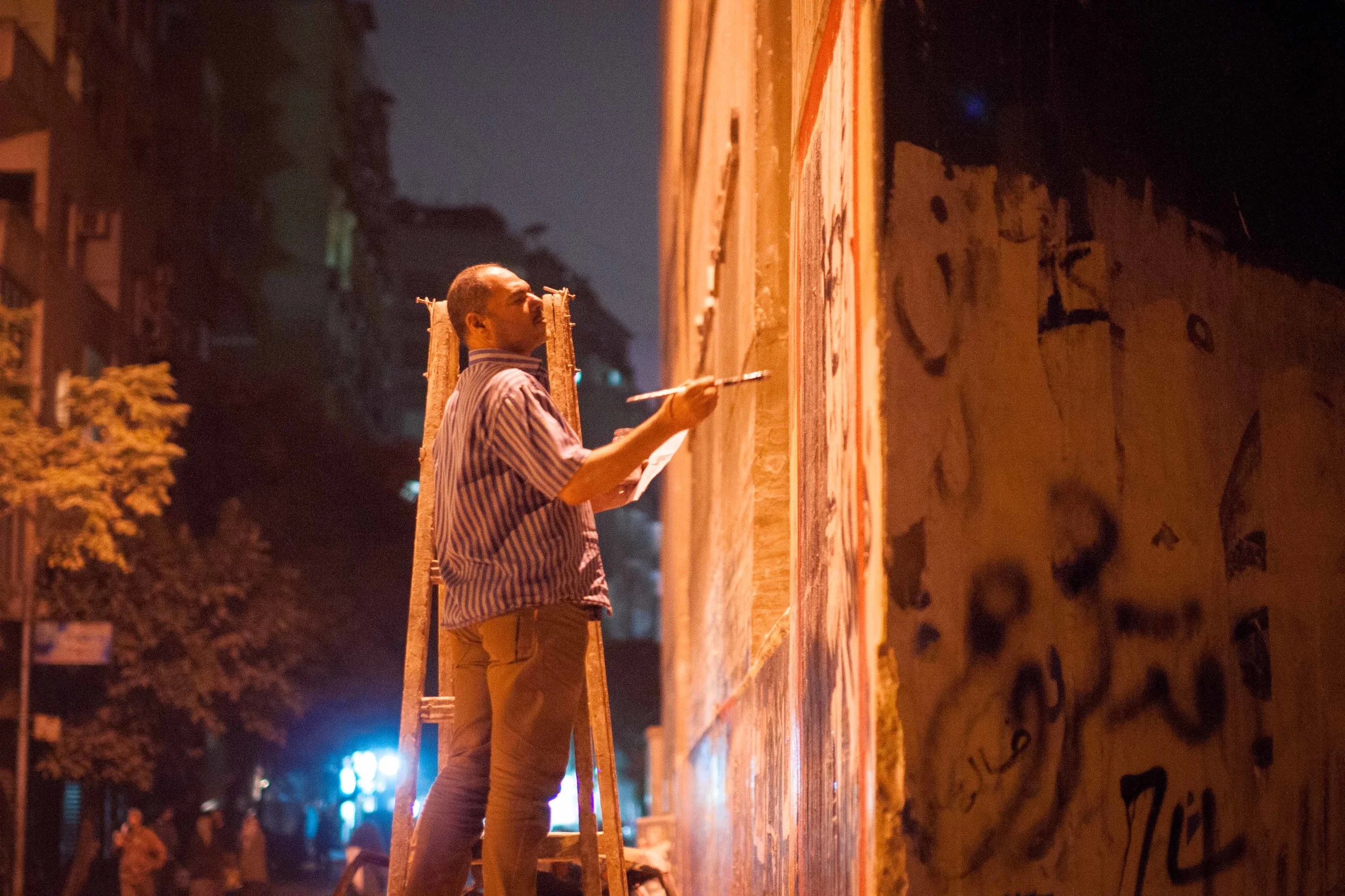 A lone artist works on his mural of famed Egyptian writer Naguib Mahfouz on Mohamed Mahmoud Street.