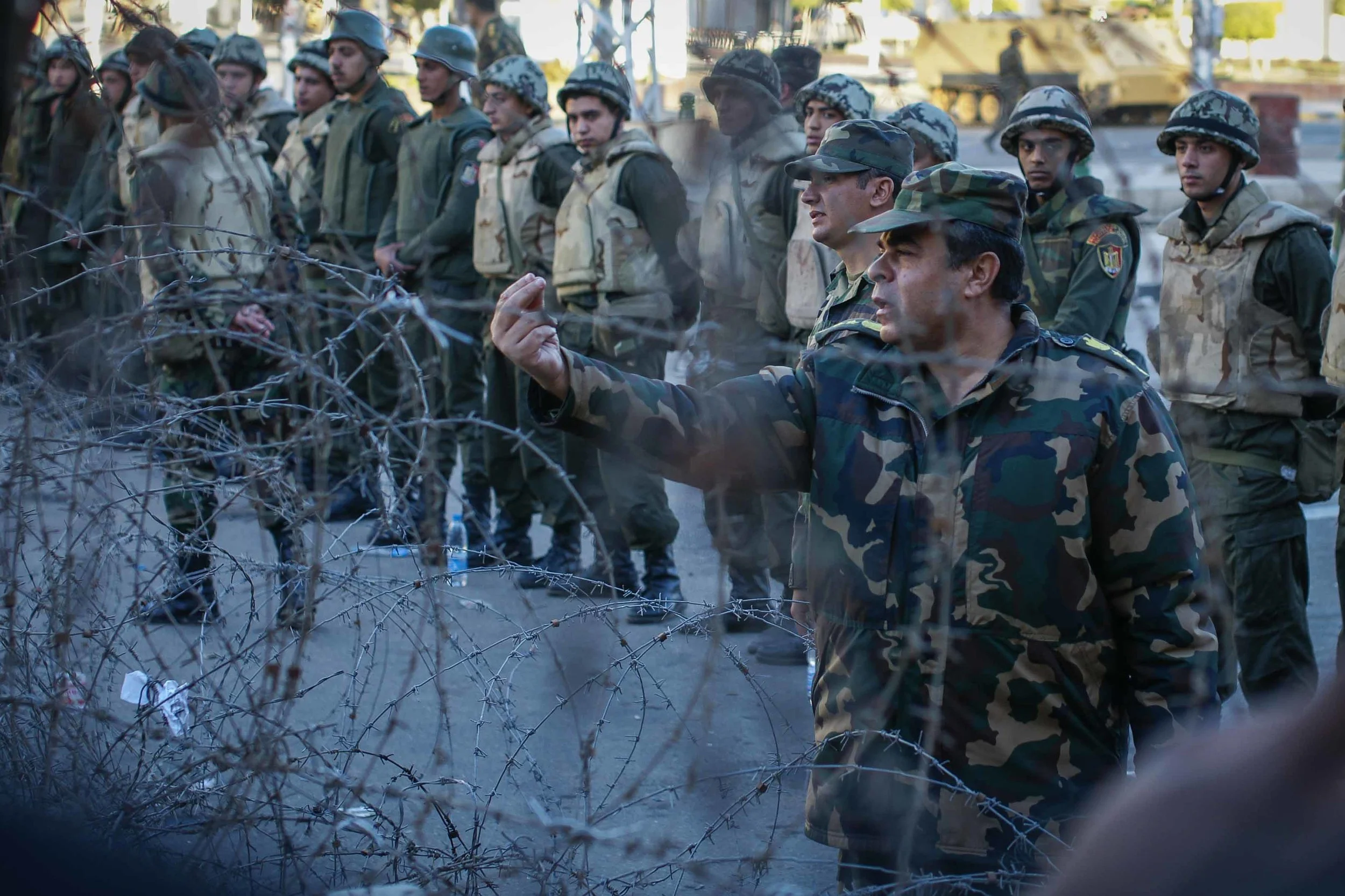 A member of the Egyptian military gestures with the sign to 'Wait!' at protestors. Protestors and the military exchanged heated words (at times) through the barbed wire.