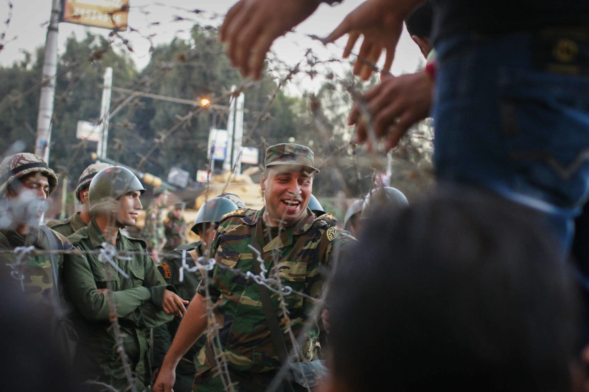 A member of the military jokes with a protestor as he is handed candy. In order to diffuse the tension, soldiers passed over Egyptian flags to the protestors, and protestors handed the soldiers candy or small items in return.