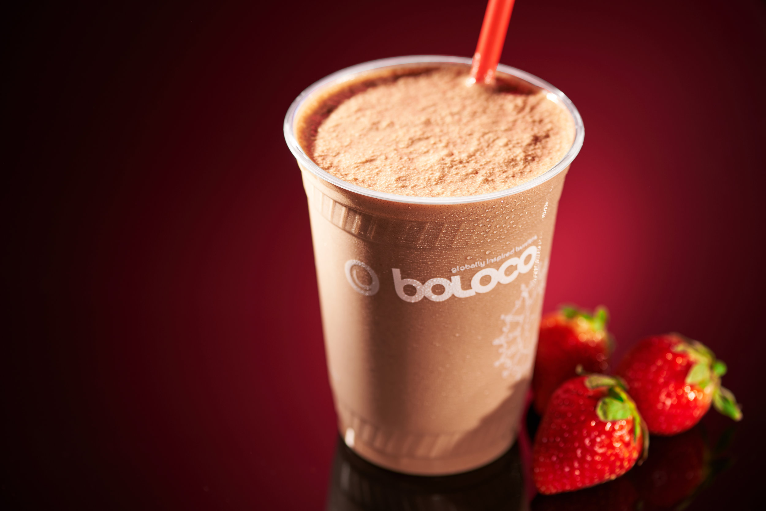 Professional food photo of a Nutella and strawberry smoothie by Boloco. Photo take in studio with a black background and a red gradient. Commercial photography