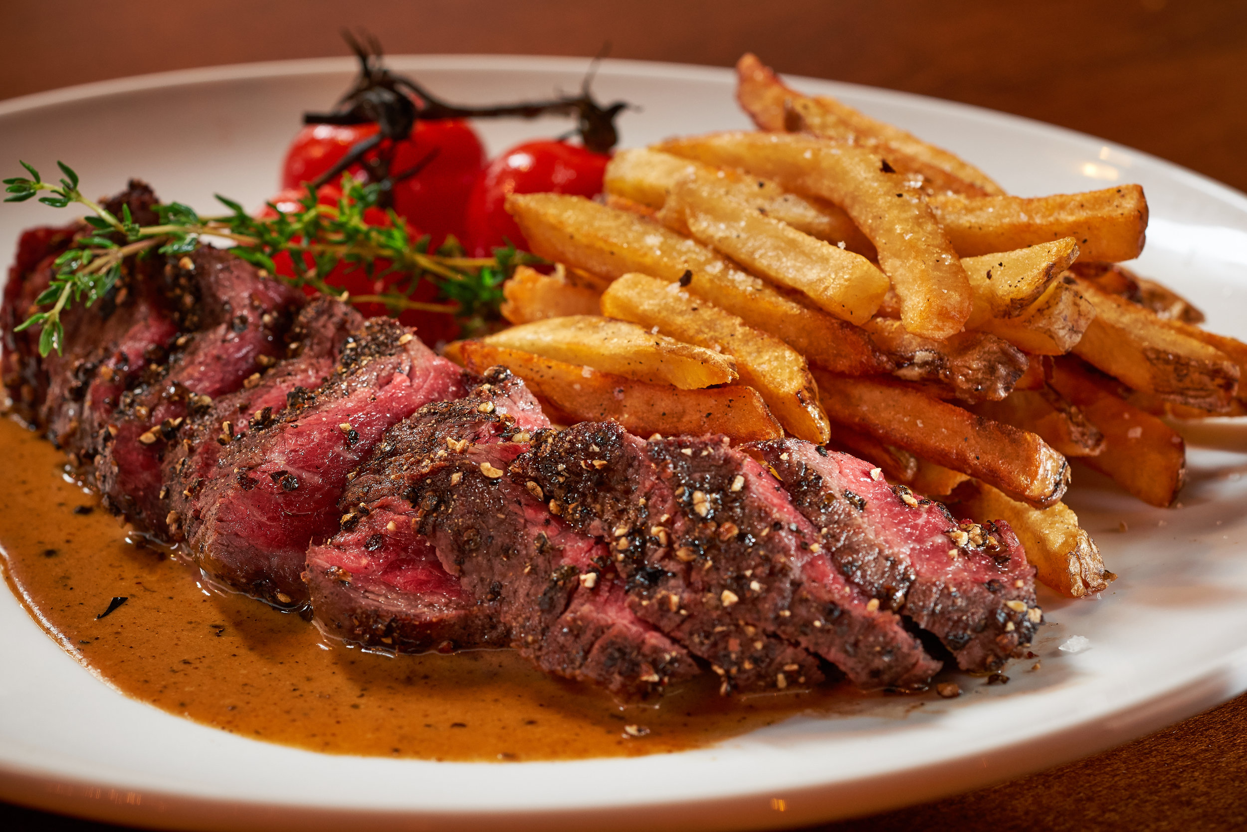 Professional food photo of juicy medium rare steak with french fries and grape tomatoes. Commercial photography