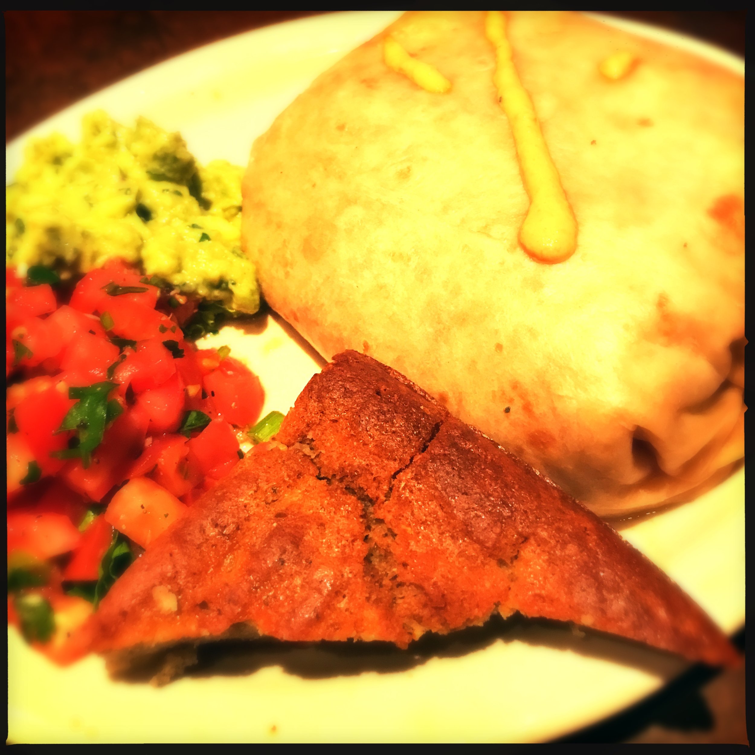 The Carnitas Burrito is served with r oasted green chilis inside, blue cornbread, pico and sweet-n-sour slaw on the side.
