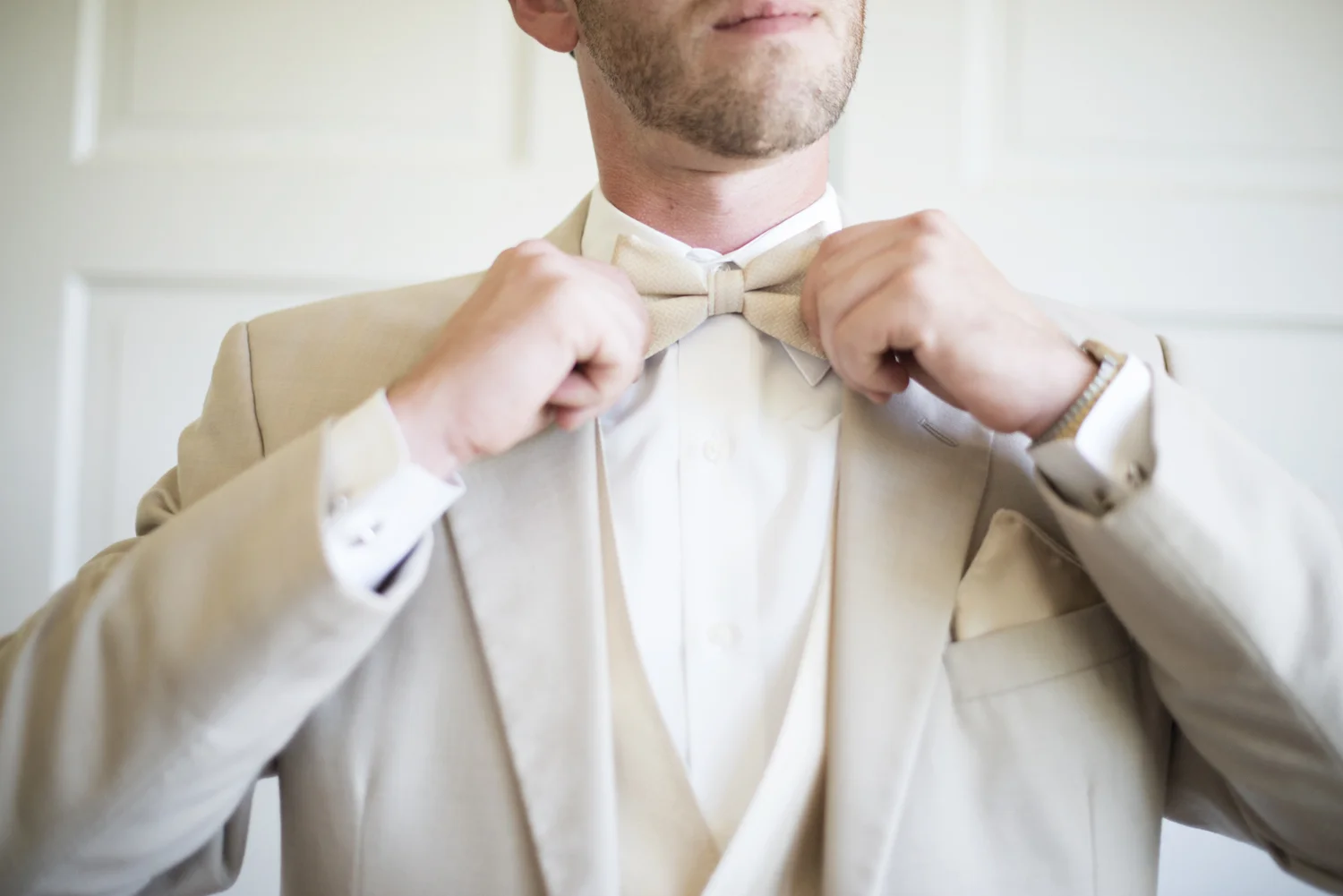 Groomsman adjusts his cream white tie | Portsmouth Woman's Club in Virginia