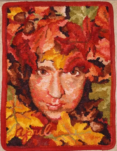 Lady Red Jack 2011, September. Faces of the Seasons Series. 15" by 19 1/2". #6 cut on linen. Designed, dyed and hooked by April DeConick. Red Jack Palette Wool: 8-value packs of Bittersweet 162, Peter Pumpkin 163, Ellendale Orange 126, Tanglewood 148, and Lake Agate 127; 1 piece of Goodfellow Yellow 105 value 5, Will 'O Wisp 158 value 5; Moorland Moss 106 dappled; 2 pieces of Sunset Gold 104 value 6; Goodfellow Yellow 105 value 7; Black Orchid 146 value 7 and 8; Will 'O Wisp 158 two textures; 4 pieces Nightshade Berry 160 four textures. 