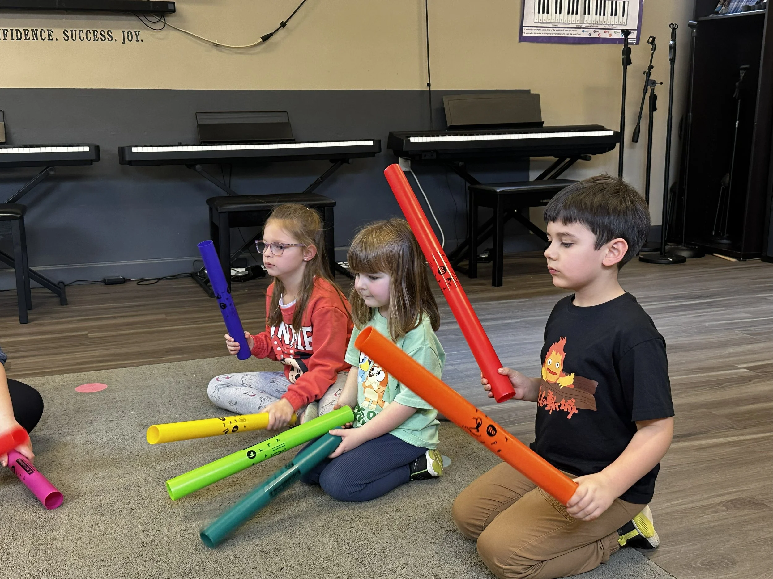 Groove Kids students follow along using Boom Whackers to keep the beat in a song.
