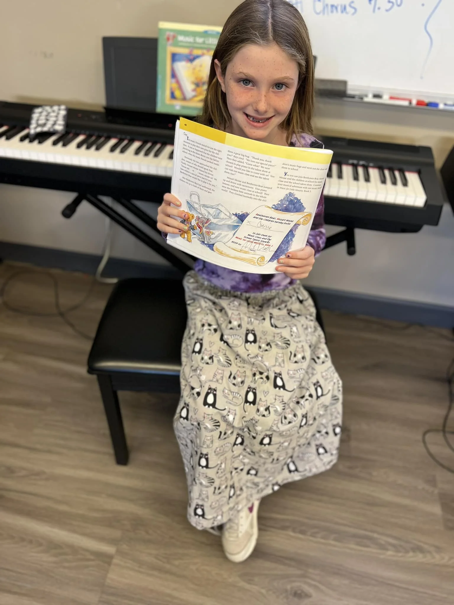 A proud student shows off her completed lesson book during piano class at the Music Studio of Patricia Keith.