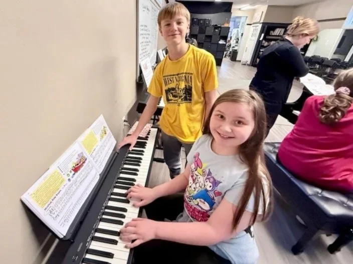 A piano student practices while an assistant guides her during a piano class at the Music Studio of Patricia Keith.