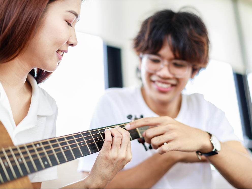 Students look at the frets on a guitar.
