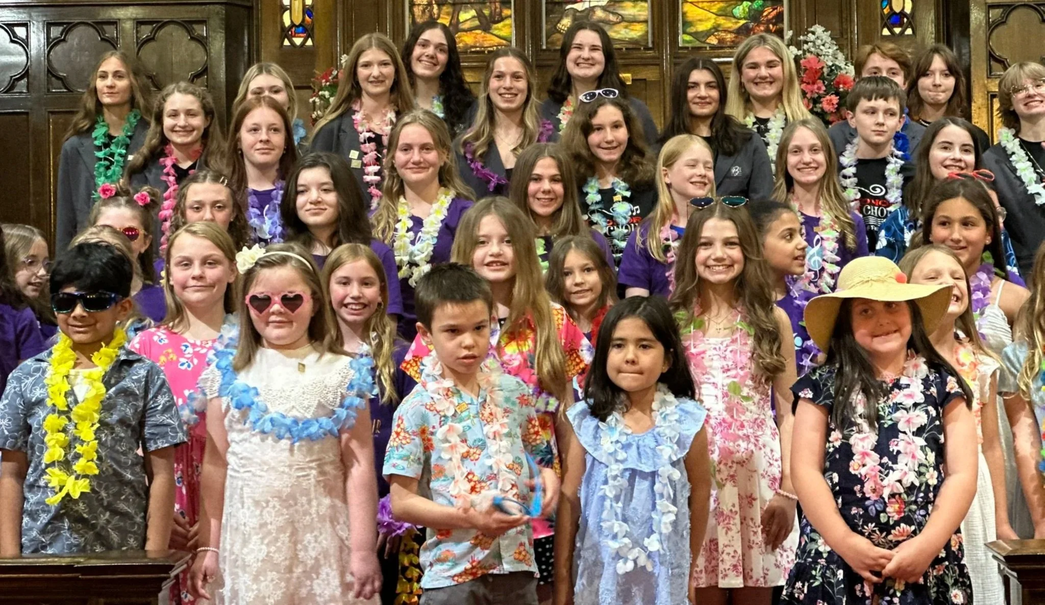 A group of students of various ages are wearing lei's and sunglasses while performing at the Collective Harmony Concert with the Music Studio of Patricia Keith in Boyertown, PA.
