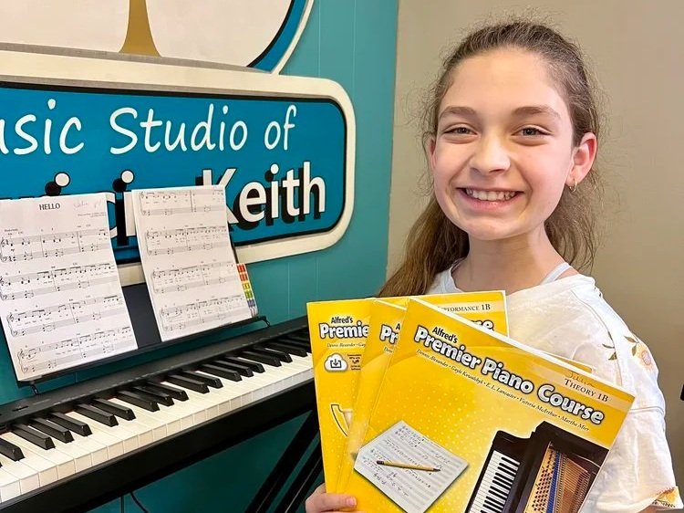 A smiling student shows off her new piano course books during a piano class at the Music Studio of Patricia Keith in Boyertown PA.