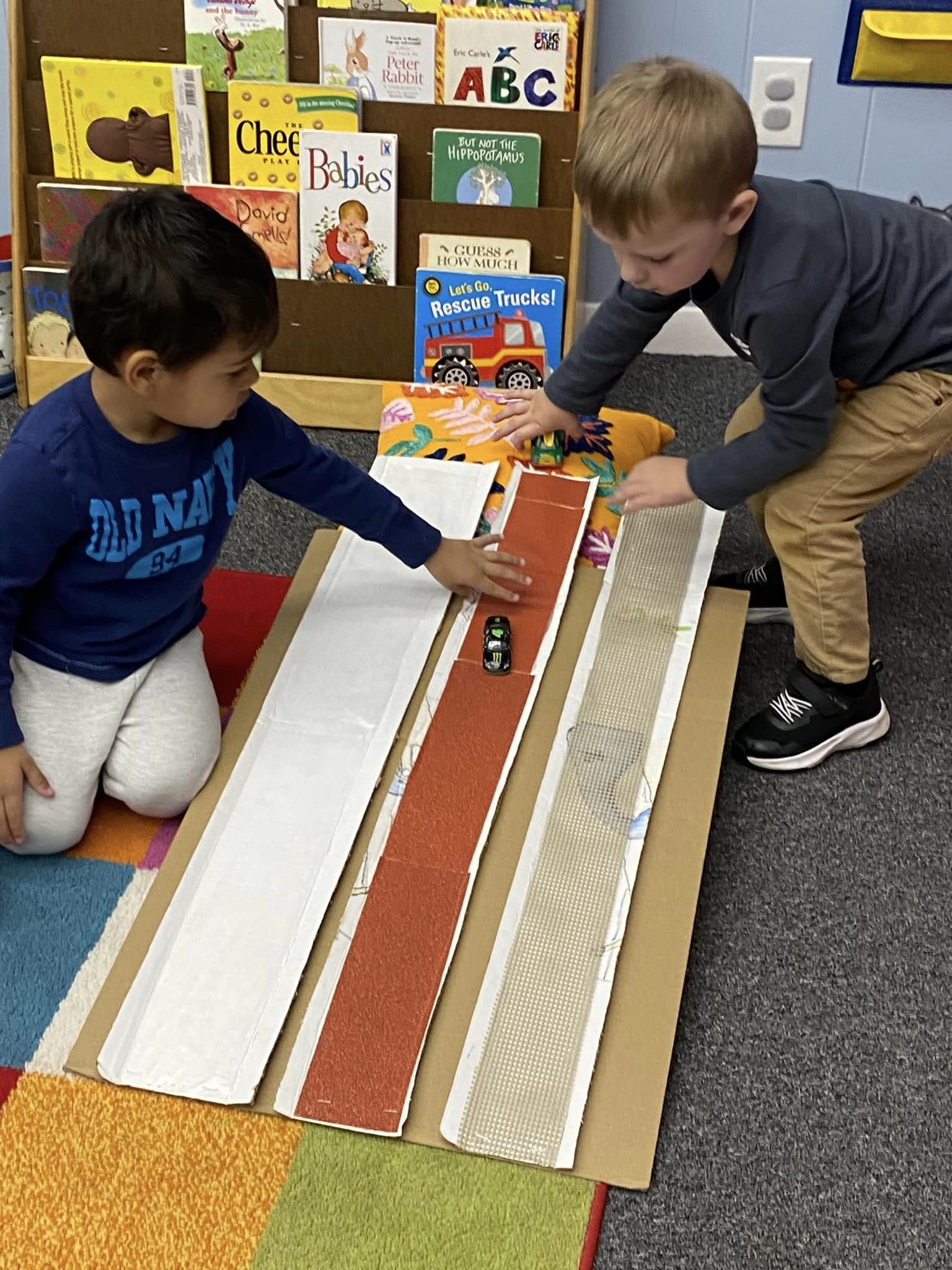 Preschool-age students playing with toy vehicles
