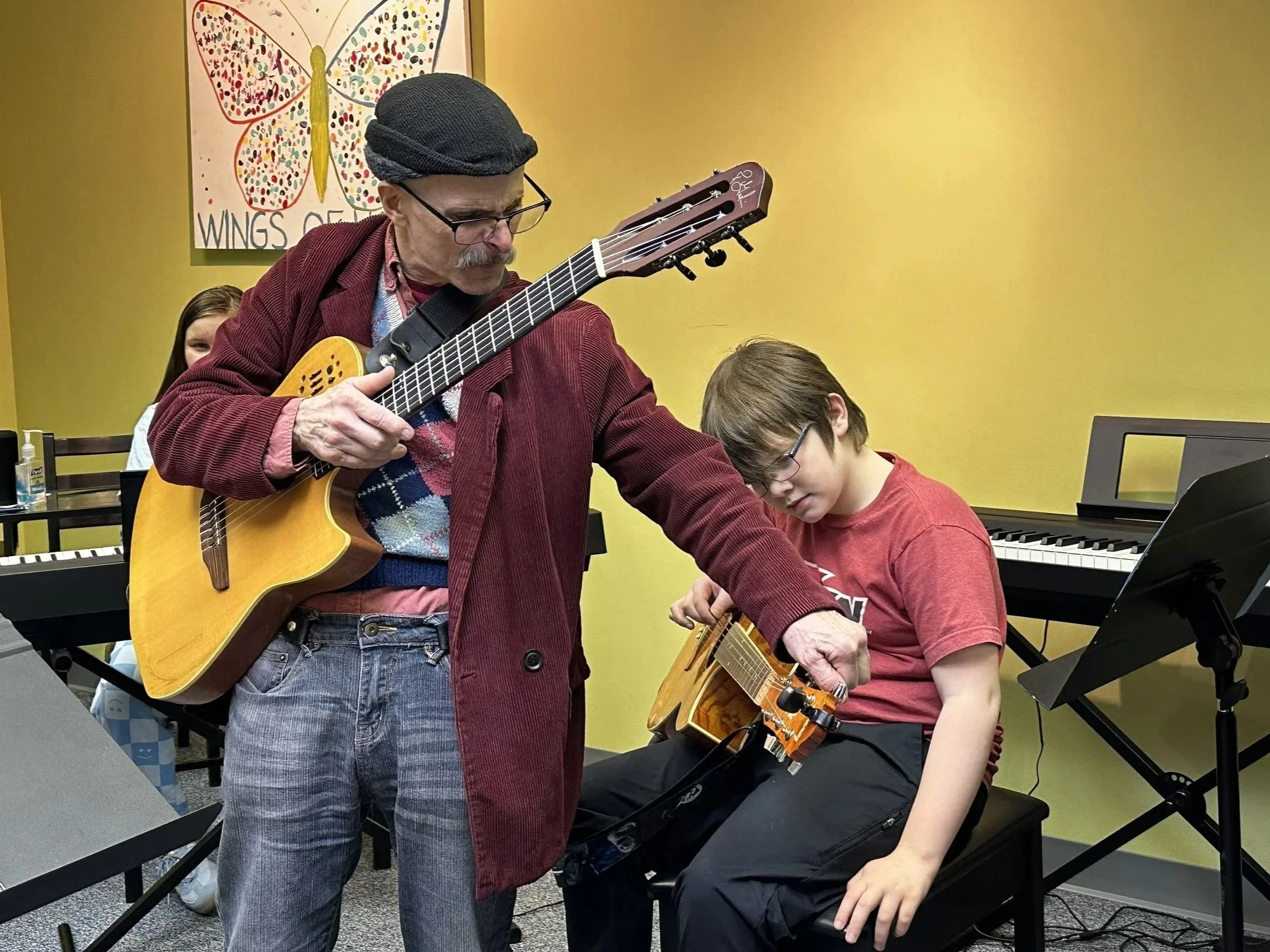 The teacher helps a student tune his guitar during class at our Boyertown studio.