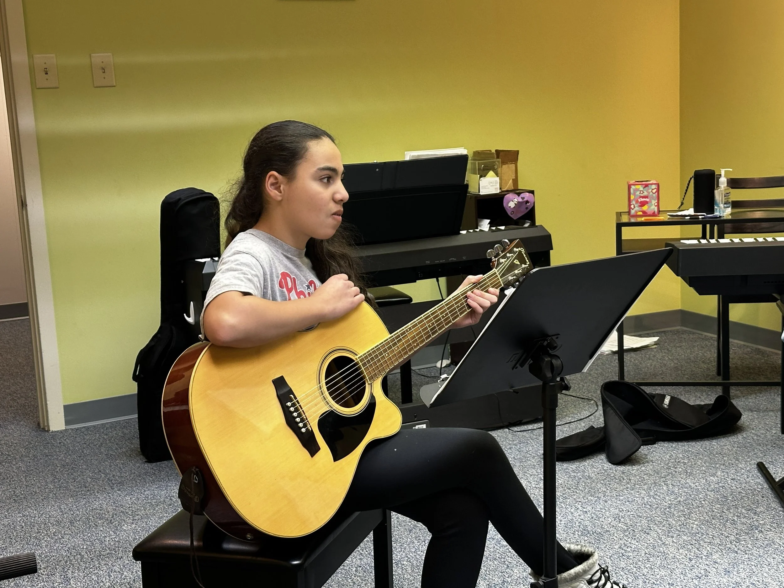 A student sits with her guitar during class at our Boyertown studio.
