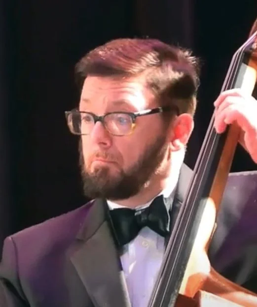 A profile picture of a man playing a large stringed instrument