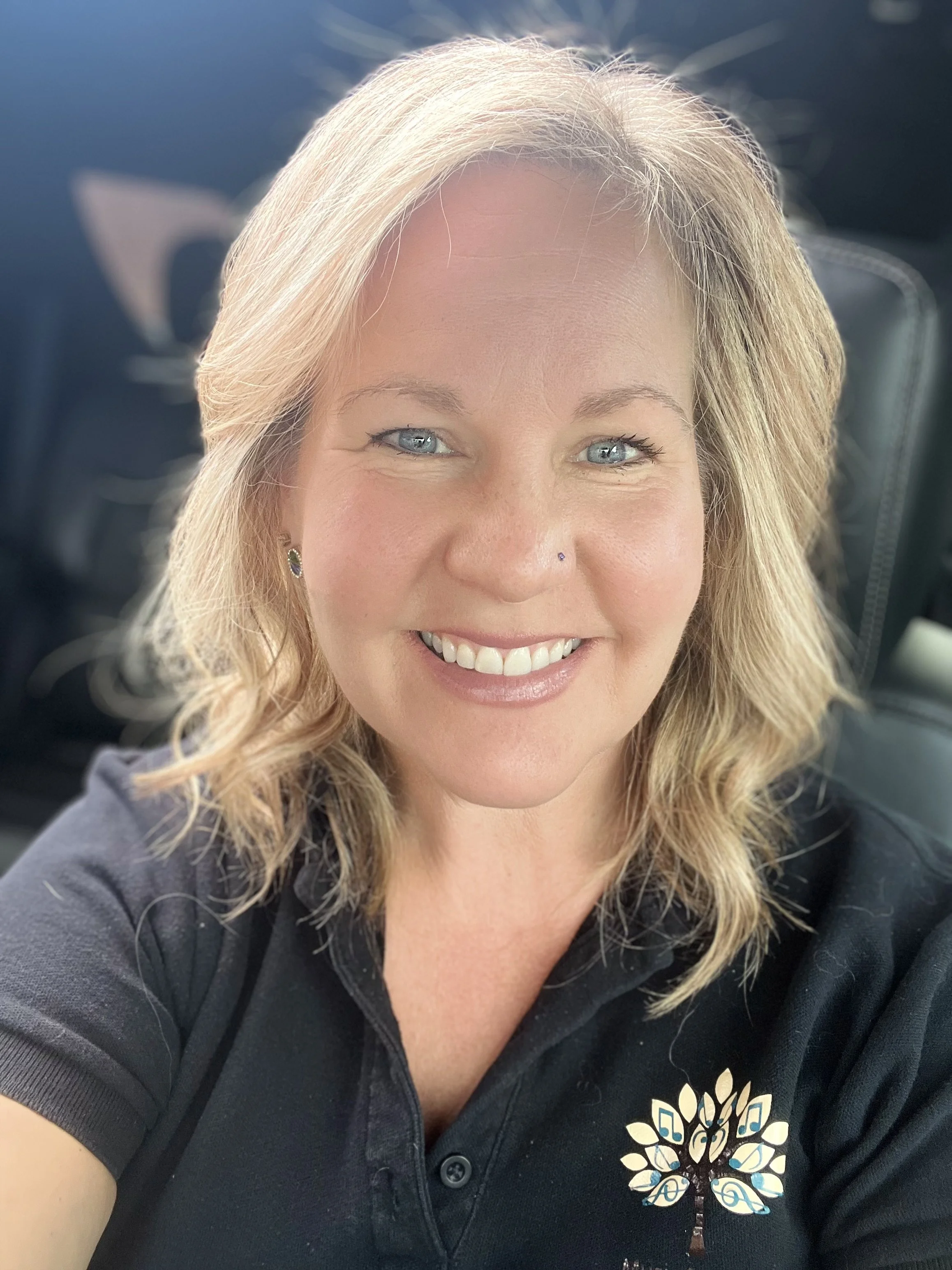 A smiling woman with blond hair and blue eyes is smiling