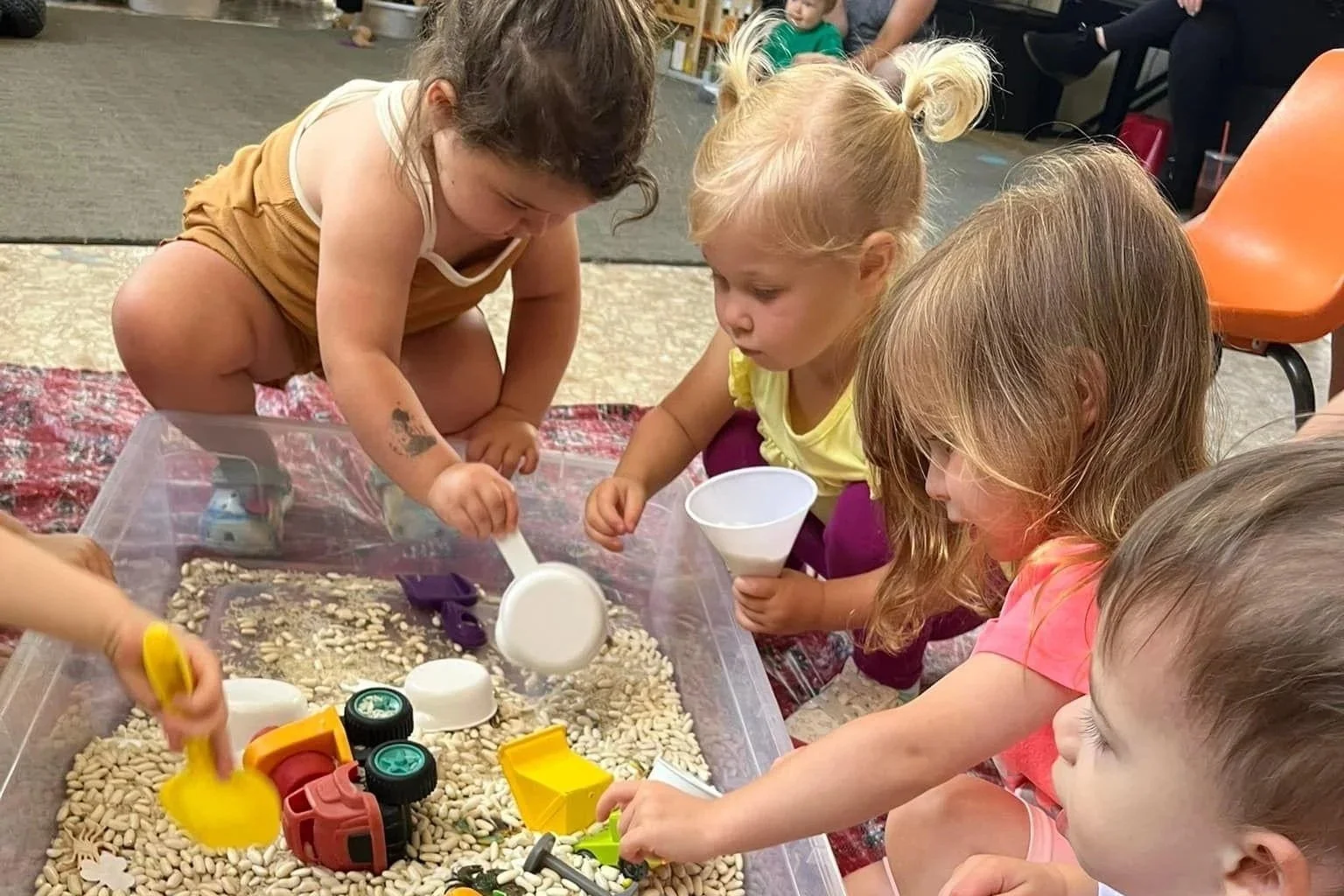 Toddlers explore a sensory bin bull of beans and toys during Busy Bees class in Boyertown PA.