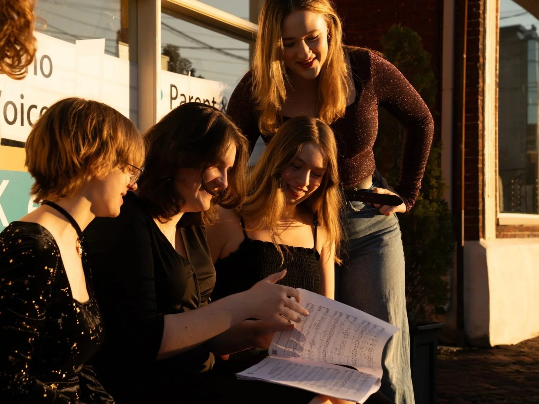 The Harmonics group reviews music outside the studio during a rehearsal break.