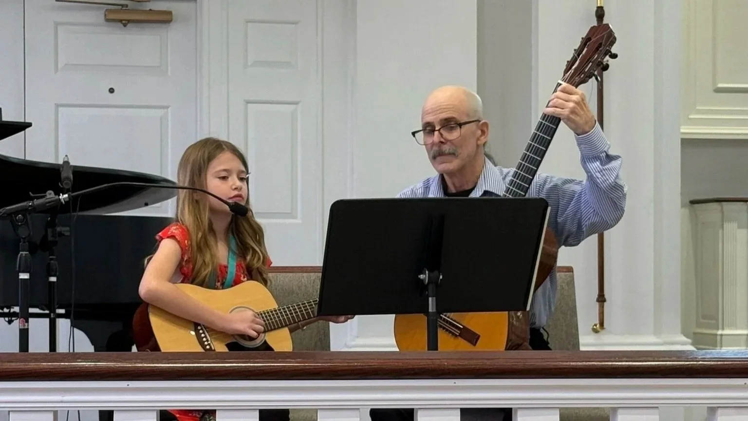 A guitar teacher and his student play a duet together at a recital hosted by the Music Studio of Patricia Keith.