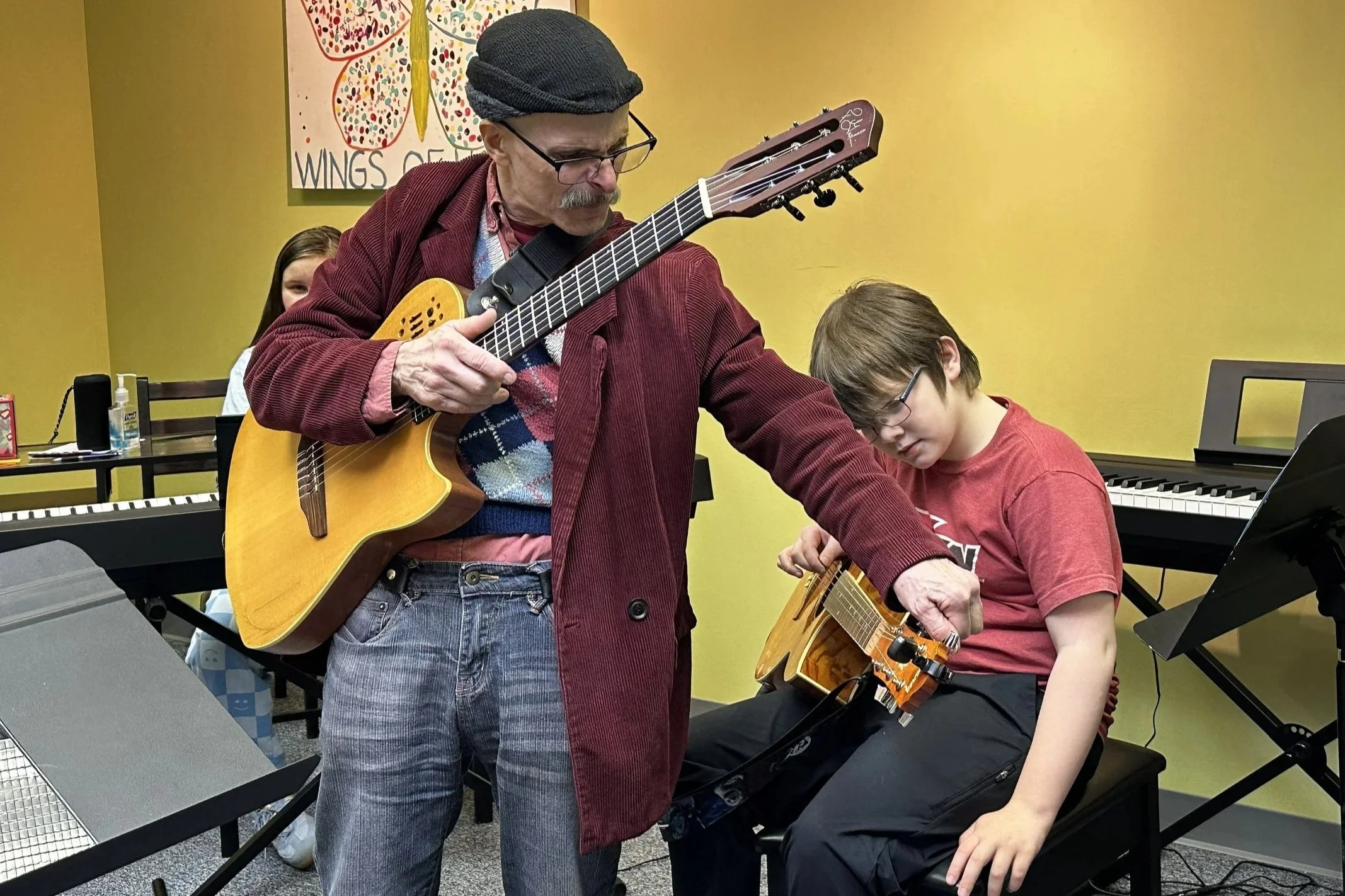 Mr. Russ helps a student adjust his guitar tuning.