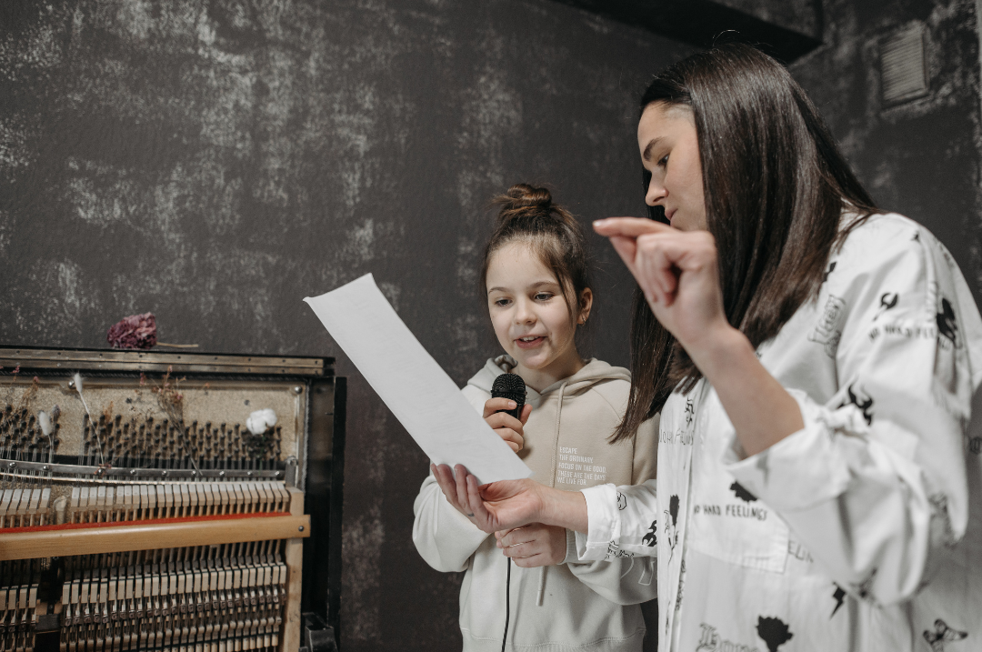 Student reading sheet music with microphone during a voice lesson with their teacher