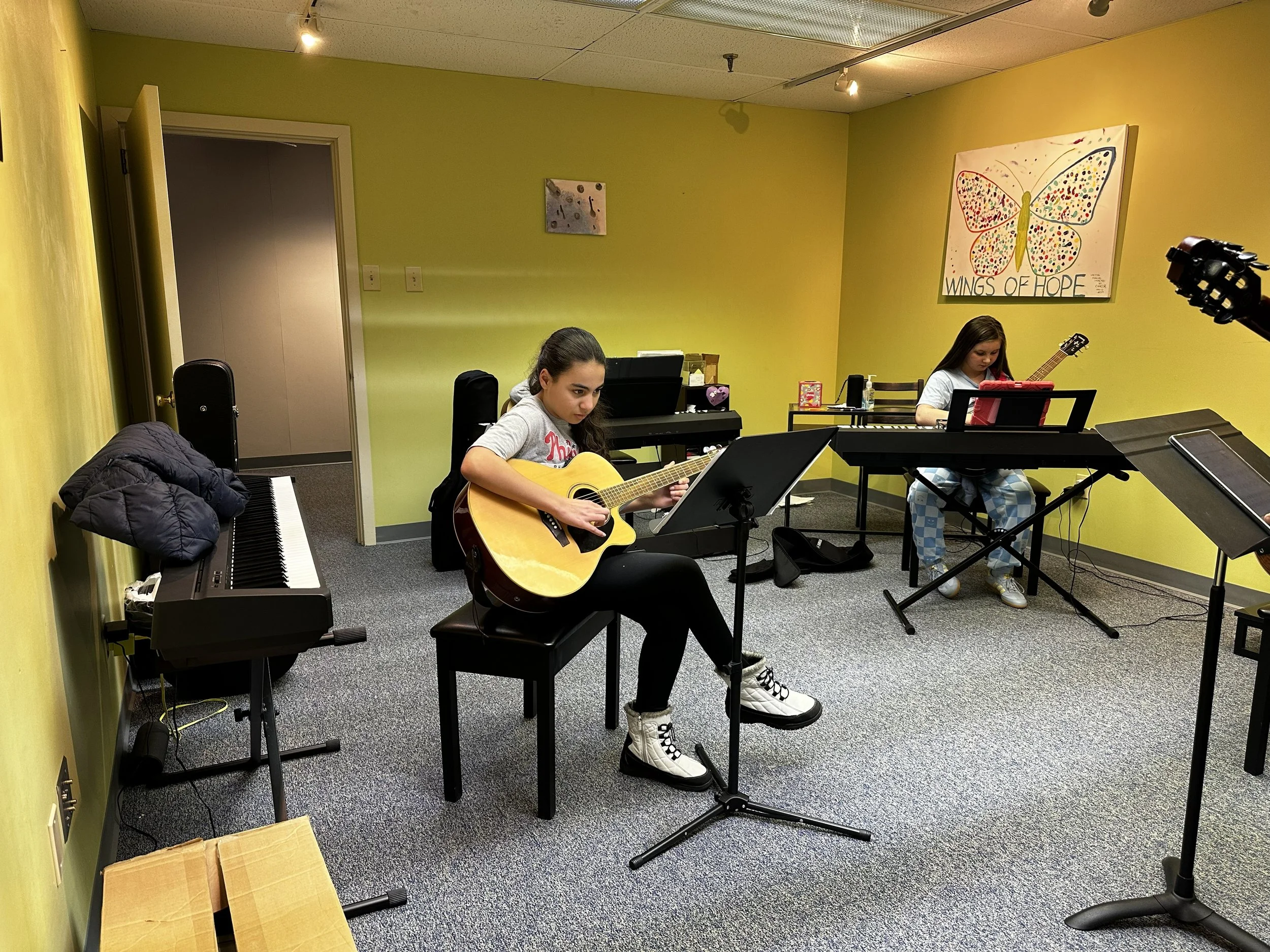 Students in guitar class concentrate while playing.
