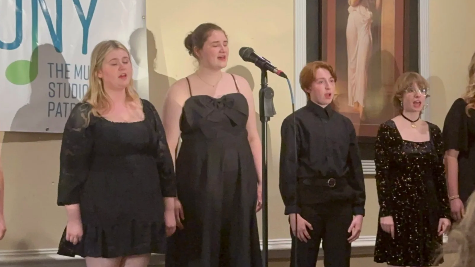 Teen vocalists are dressed formally, performing on stage at a Cabaret performance.