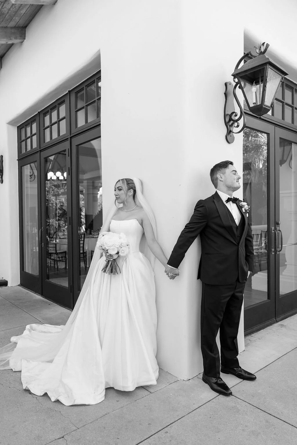 Bride and groom holding hands against joint walls right before they see each other for the first time before getting married