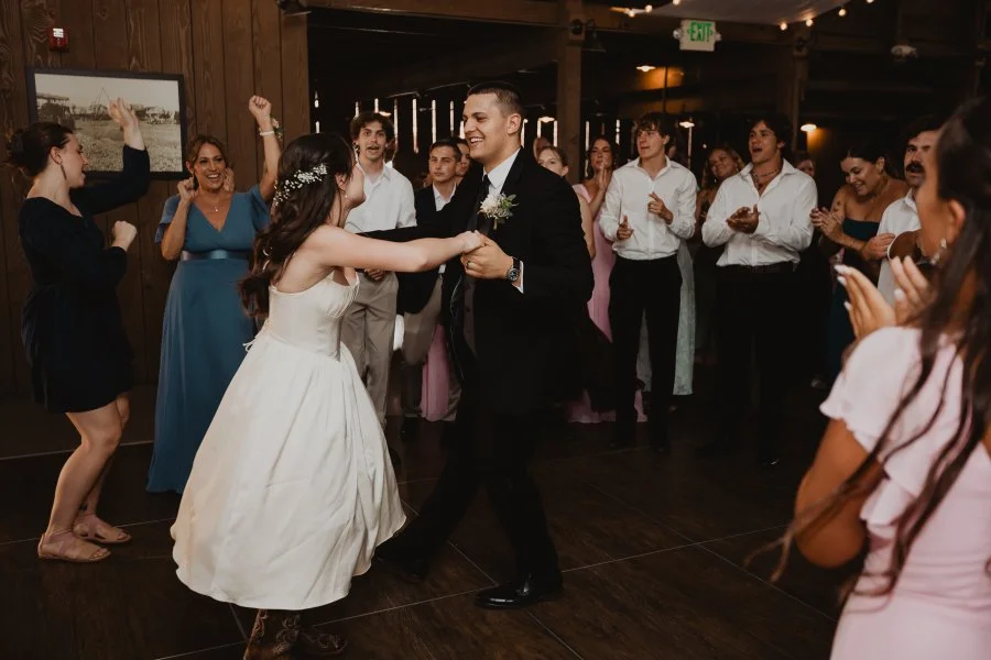 Bride and groom dancing at the Camarillo Ranch House with family and friends circling around them