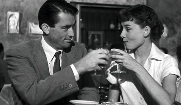 Audrey Hepburn and Gregory Peck drinking champagne at a Roman Cafe in Roman Holiday.