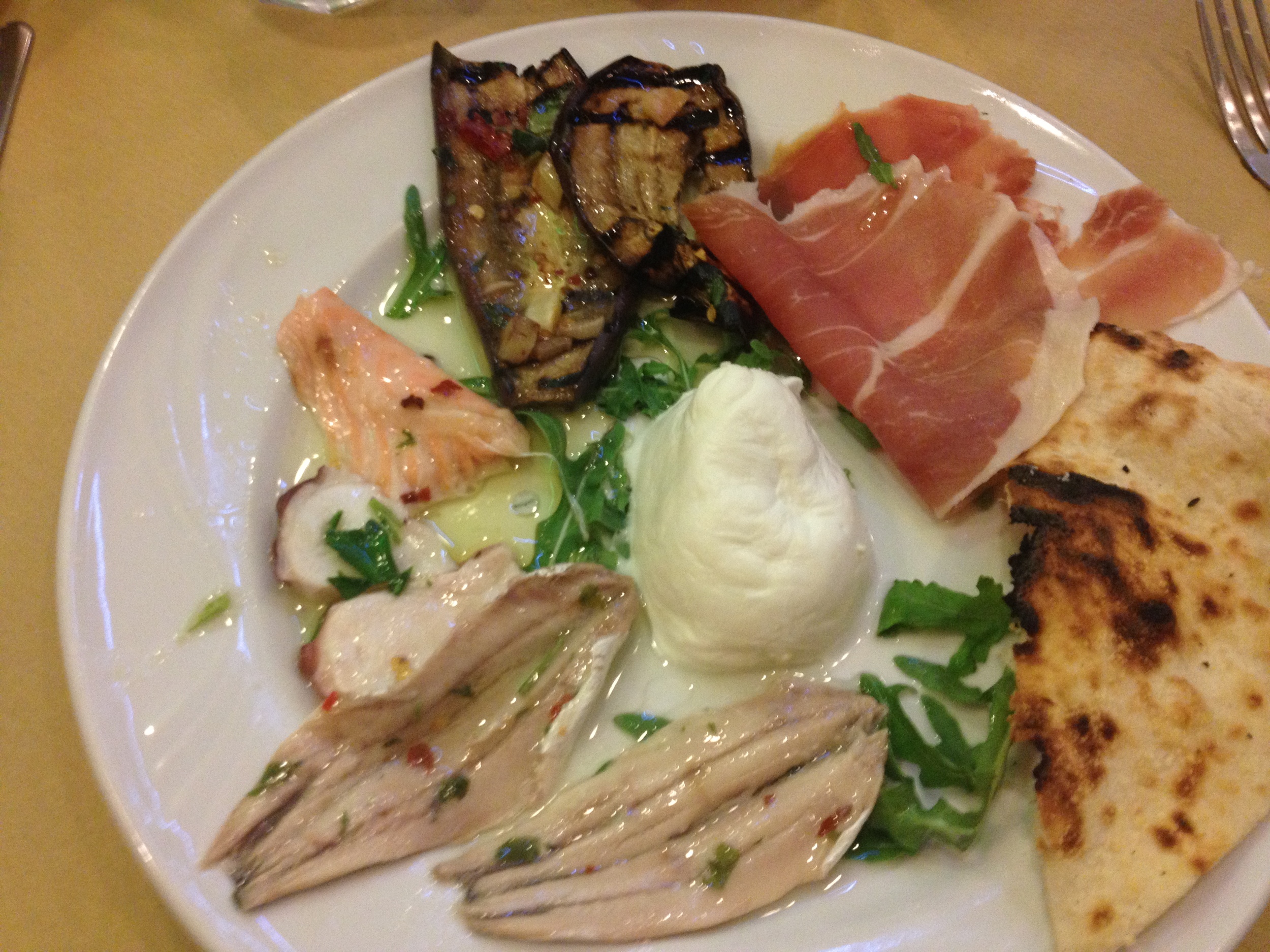 Amazing apertivo at a small local restaurant in the Spanish Quarter of Naples featuring an assortment of fish, buffalo mozzarella, arugula, and bread.