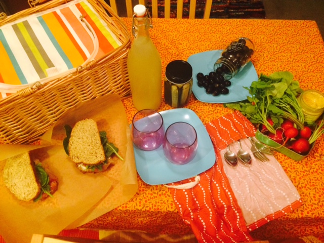 An assortment of easy-to-prepare goodies and reusable dishes ready for the basket.