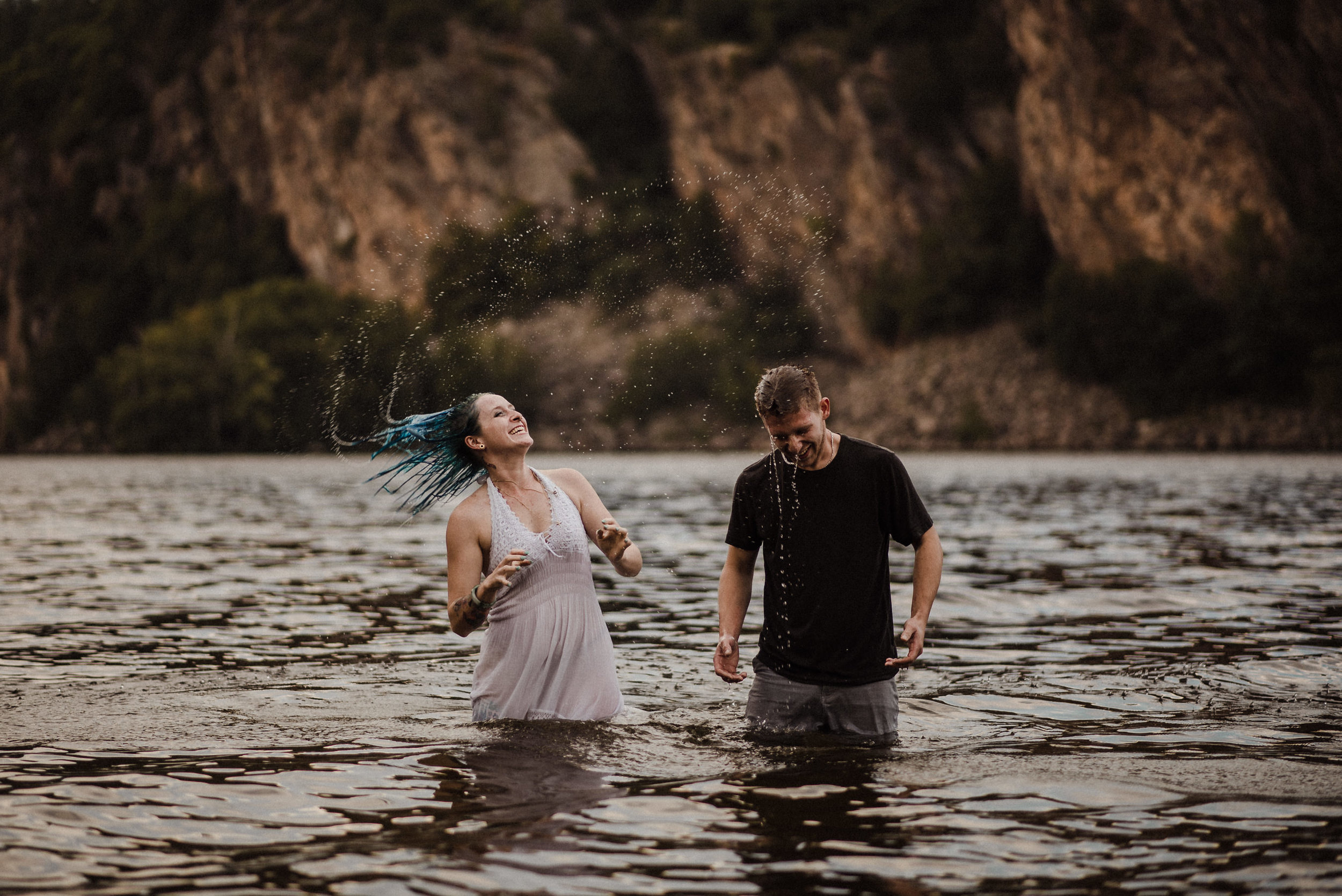 engaged couple jumping in lake