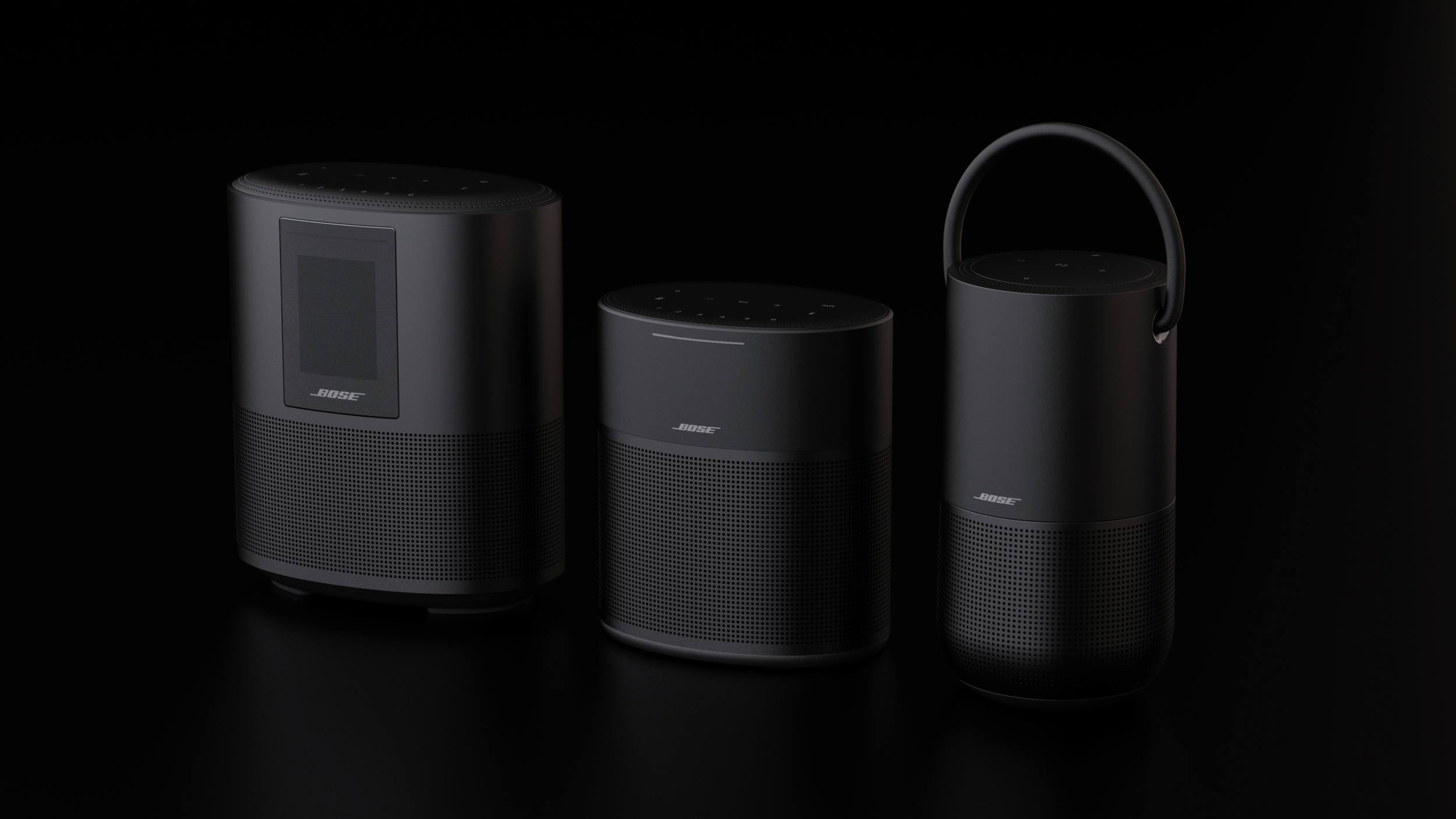 Three Bose smart speakers with sleek, black design against a dark background.