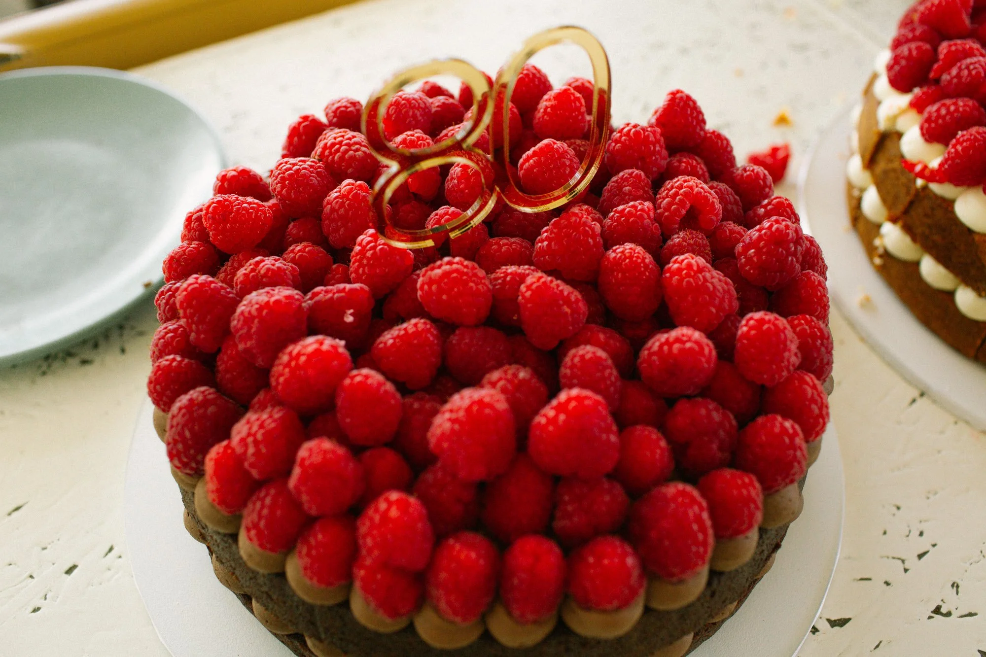 Round chocolate cake topped with fresh raspberries and chocolate decorations