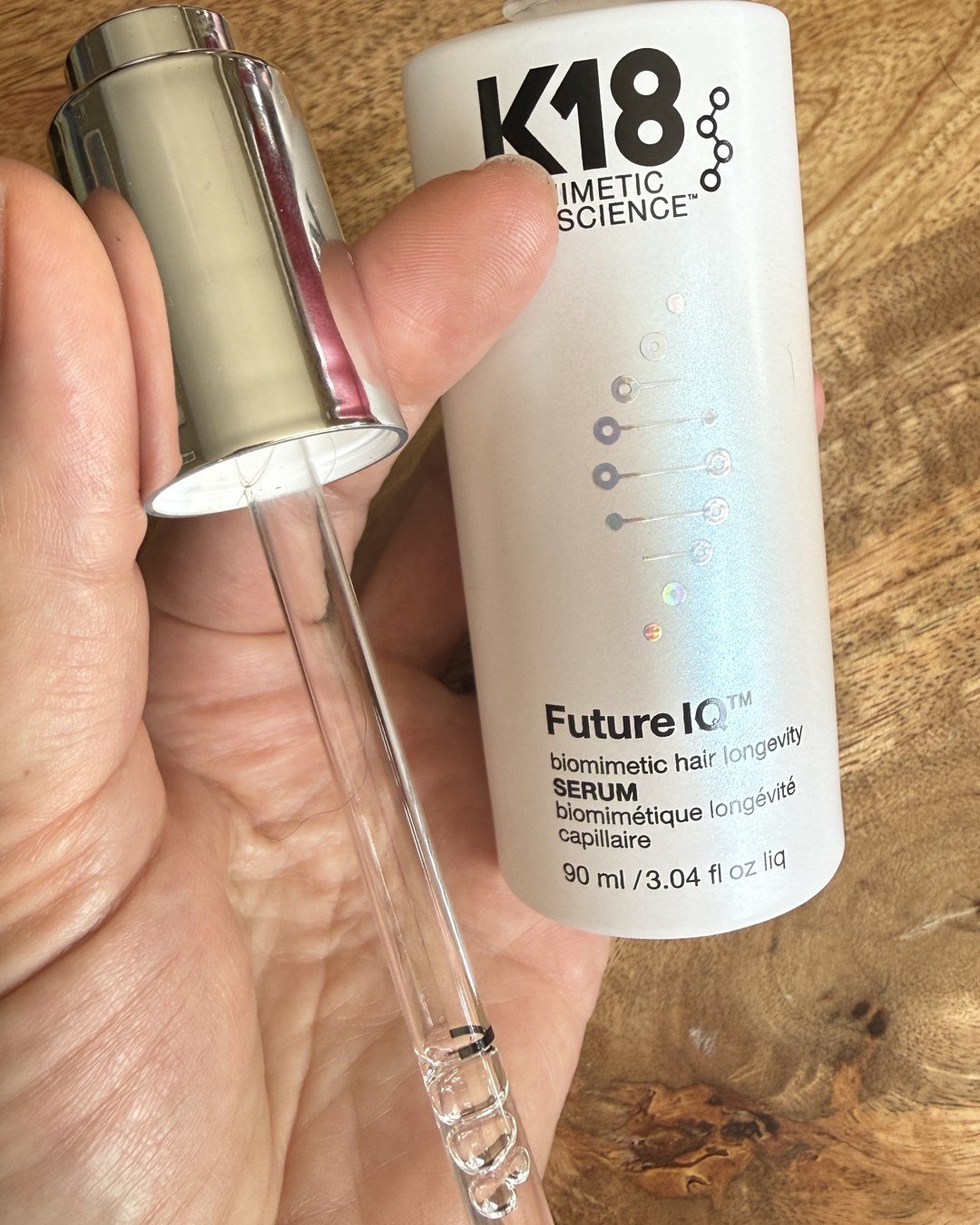 K18 FutureIQ serum dropper filled to the line, held next to the open bottle