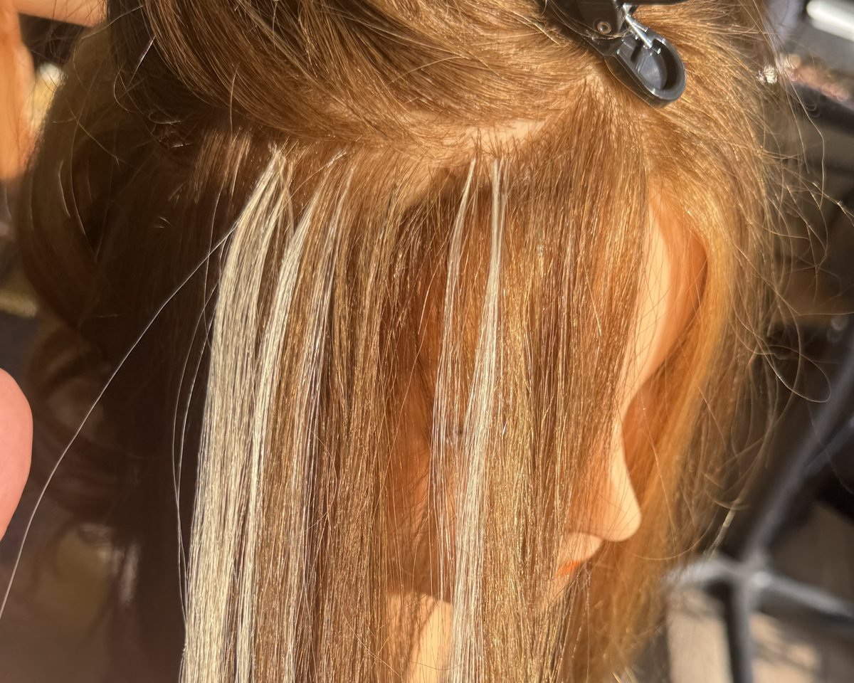 Blonde V-light hair extension strands applied close to the scalp