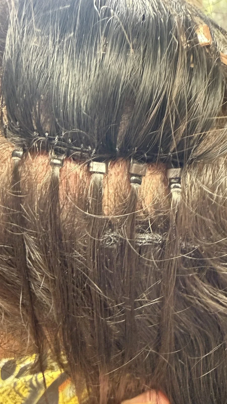 Row of microbead hair extensions on brunette hair at a Boise salon