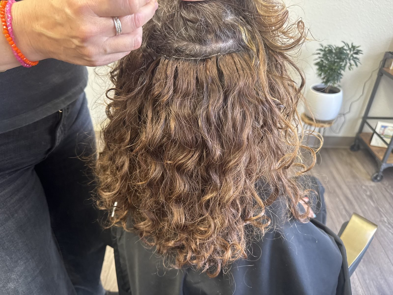 Hair extensions blended into natural curly brown hair at Fusion Studio in Boise