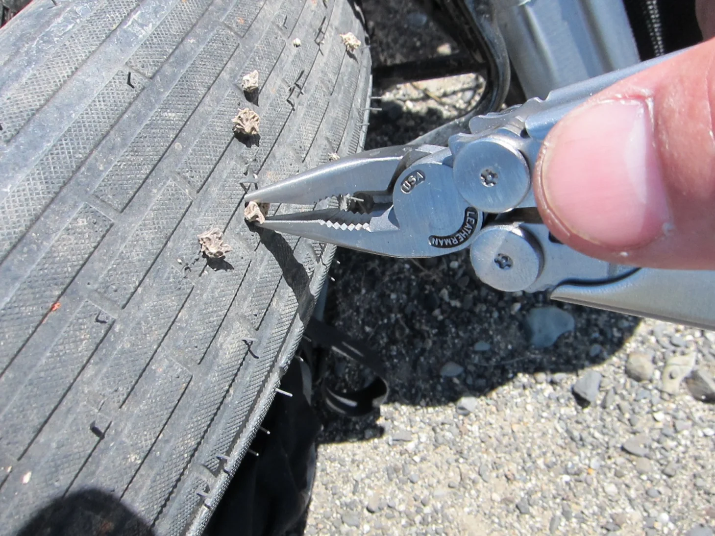 Pat pulling dozens of thorns out of a fat tire using pliers.