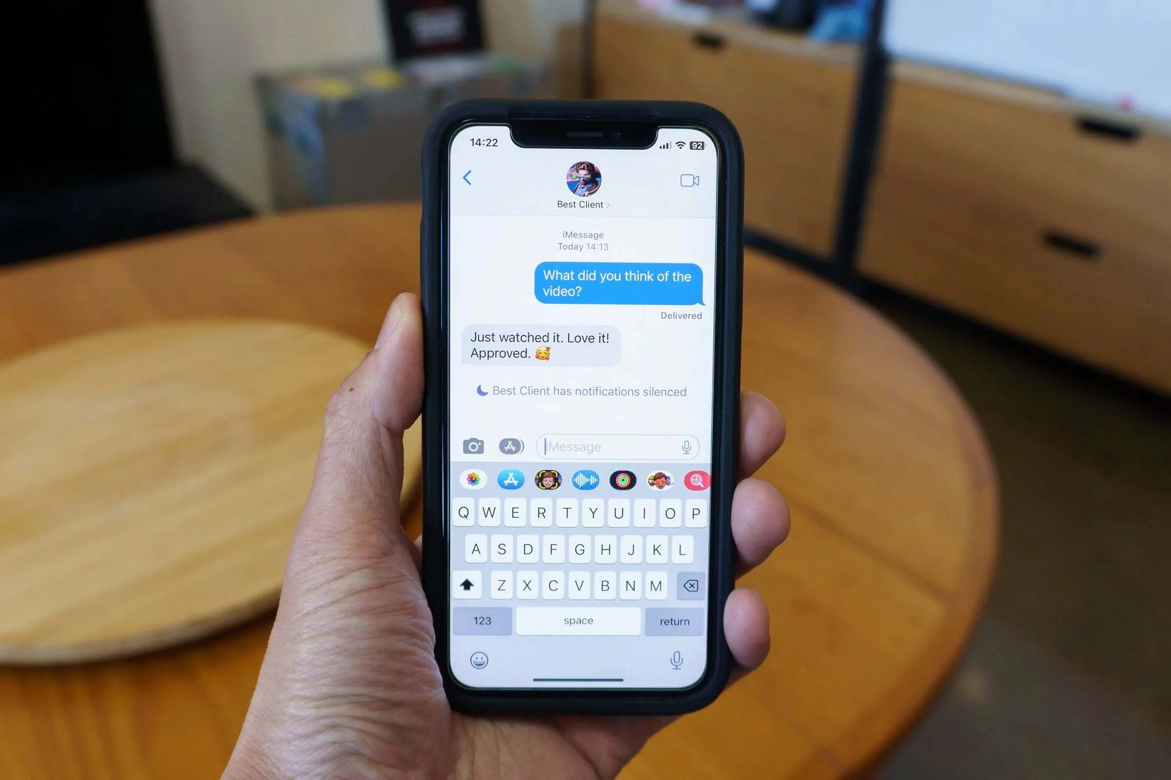 Close-up of a person holding a smartphone, displaying a messaging conversation with a contact labeled 'Best Client.'