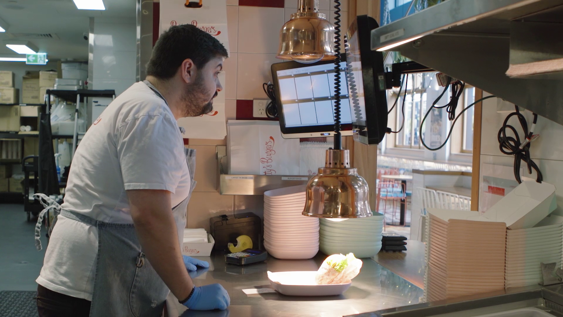 A man working in a restaurant kitchen preparing food, with plates and kitchen equipment around him.
